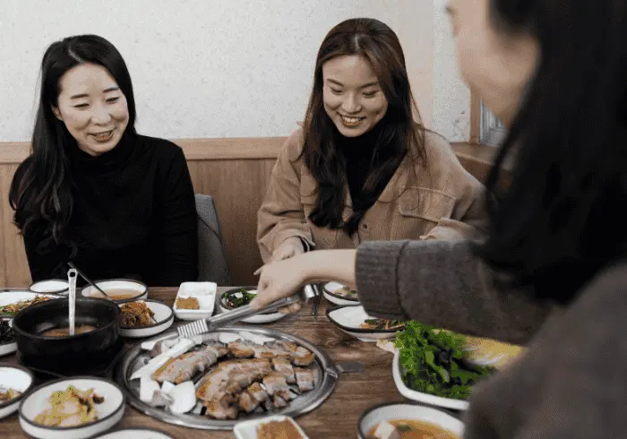Grupa koreańskich znajomych siedzących wspólnie w restauracji, kierunek wschód, język koreański