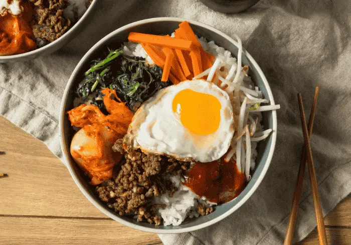 Różnorodne potrawy kuchni koreańskiej, w tym miski z bibimbap i tradycyjne przystawki, prezentujące autentyczne smaki Korei.