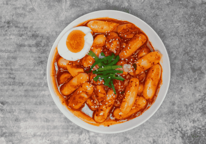 Tradycyjne tteokbokki, pikantne danie kuchni koreańskiej z ryżowych klusek w sosie gochujang, ukazujące autentyczne smaki Korei.